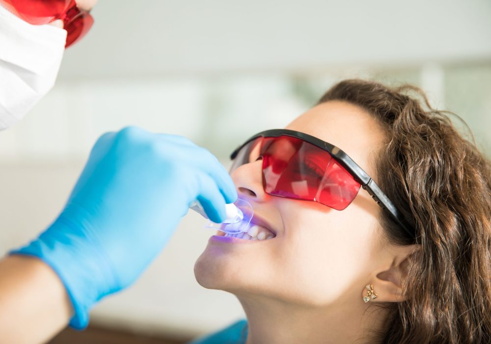 Closeup of young woman having her teeth whitened with ultraviolet light in a dental clinic